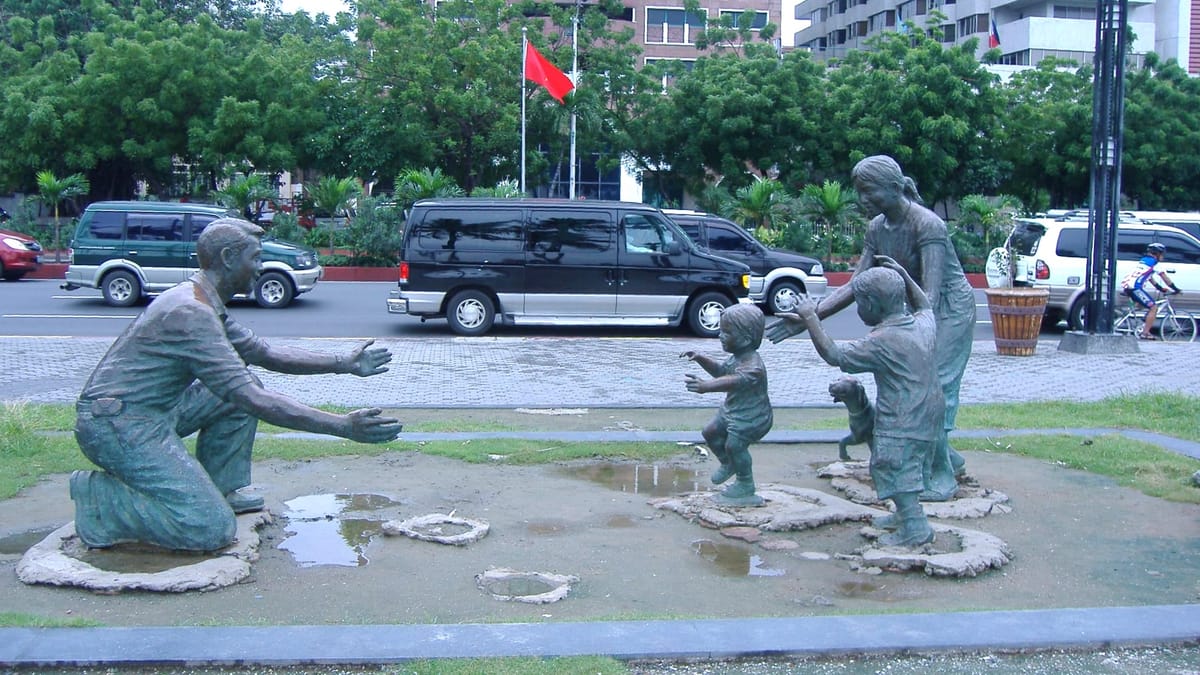 A scultputre of a father in one knee greeting his family with children running towards and mother all with outstretched arms.