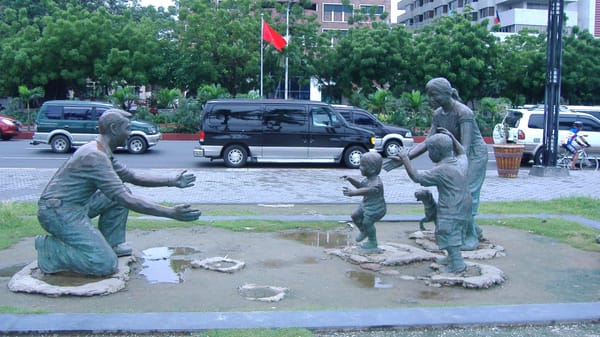 A scultputre of a father in one knee greeting his family with children running towards and mother all with outstretched arms.